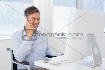 Casual businessman in wheelchair working at his desk