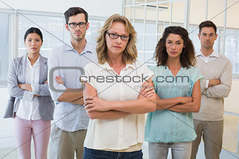Casual business team frowning at camera with arms crossed