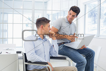 Casual businessman in wheelchair talking with colleague
