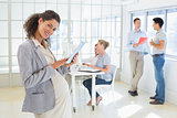 Pregnant businesswoman using tablet with team behind her