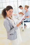 Pregnant businesswoman smiling at camera with team behind her