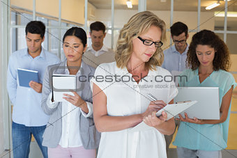 Casual boss standing in front of her team all taking notes