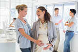 Casual businesswoman touching her pregnant colleagues belly