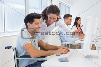 Casual businessman in wheelchair working at his desk with colleague