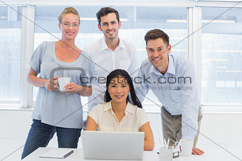 Casual business team using laptop together at desk