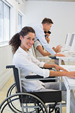 Casual businesswoman in wheelchair working at her desk