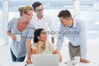 Casual business team using laptop together and smiling