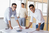 Casual architecture team working together at desk smiling at camera