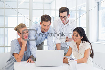 Casual business team looking at laptop together