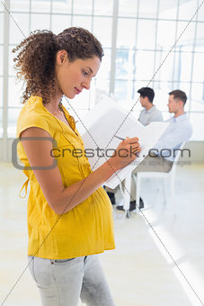 Casual pregnant businesswoman writing in folder