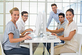 Casual business team smiling at camera at desk