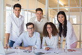 Casual business team working together at desk smiling at camera