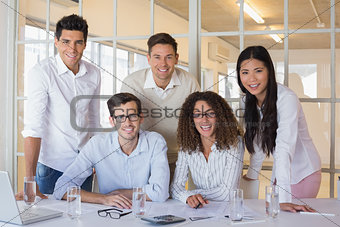 Casual business team working together at desk smiling at camera