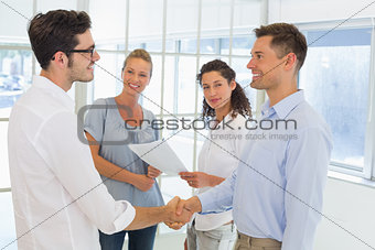 Casual businessmen shaking hands and smiling