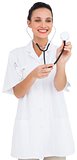 Pretty brown haired nurse listening with stethoscope