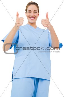 Pretty surgeon in blue scrubs giving thumbs up
