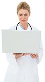 Blonde doctor in lab coat using laptop