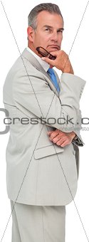 Thinking mature businessman holding glasses