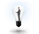 Businessman holding laptop in light bulb