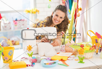 Happy young woman making easter pot holder mitts in studio