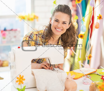 Smiling young woman making easter pot holder mitts in studio