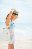 Relaxed young woman in hat with bag on beach