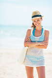 Portrait of happy young woman in hat with bag on beach
