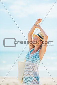 Happy young woman in hat with bag relaxing on beach