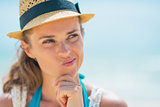 Portrait of thoughtful young woman in hat on beach