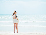 Young woman in hat with bag standing near sea