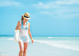 Young woman in hat with bag walking at seaside
