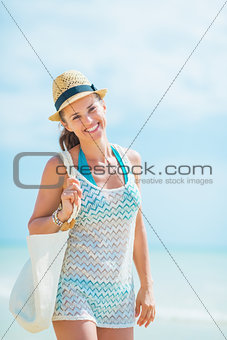 Young woman in hat with bag walking on sea coast