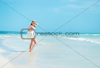 Young woman in hat with bag on sea shore