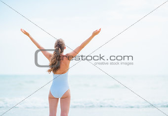 Young woman in swimsuit rejoicing at seaside