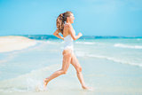 Happy young woman in swimsuit running into sea