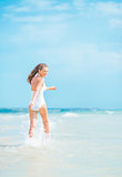 Cheerful young woman in swimsuit walking on sea shore