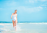 Young woman in swimsuit walking on sea shore