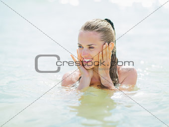 Happy young woman in swimsuit at sea looking on copy space