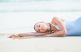 Young woman in swimsuit laying on sea shore