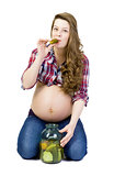Pregnant young woman on a white background eats pickled cucumber