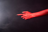 Red devil pointing hand with black sharp nails, extreme body-art