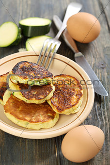 Zucchini fritters and fork on a plate.