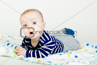 cute baby in striped clothes lying down on a blanket