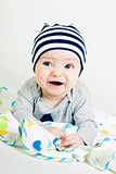 cute baby in striped hat lying down on a blanket