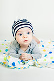 cute baby in striped hat lying down on a blanket