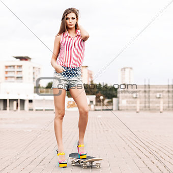 beautiful lady in short jeans shorts stands on skateboard