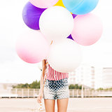 young beautiful lady holding bunch of bright balloons
