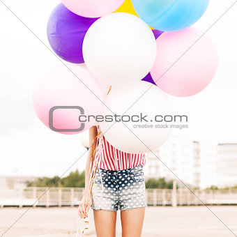 young beautiful lady holding bunch of bright balloons