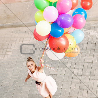 beautiful lady in retro outfit holding a bunch of balloons betwe