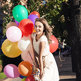 beautiful lady in retro outfit holding a bunch of balloons in ci